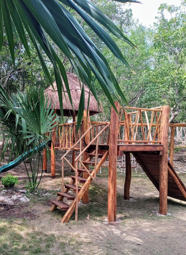Eine Spielanlage aus Holz im Dschungelstil mit Rutschen und Treppen.