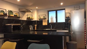 Eine moderne Küche mit Marmorarbeitsplatte, Edelstahlgeräten und einer Bar mit Hockern.