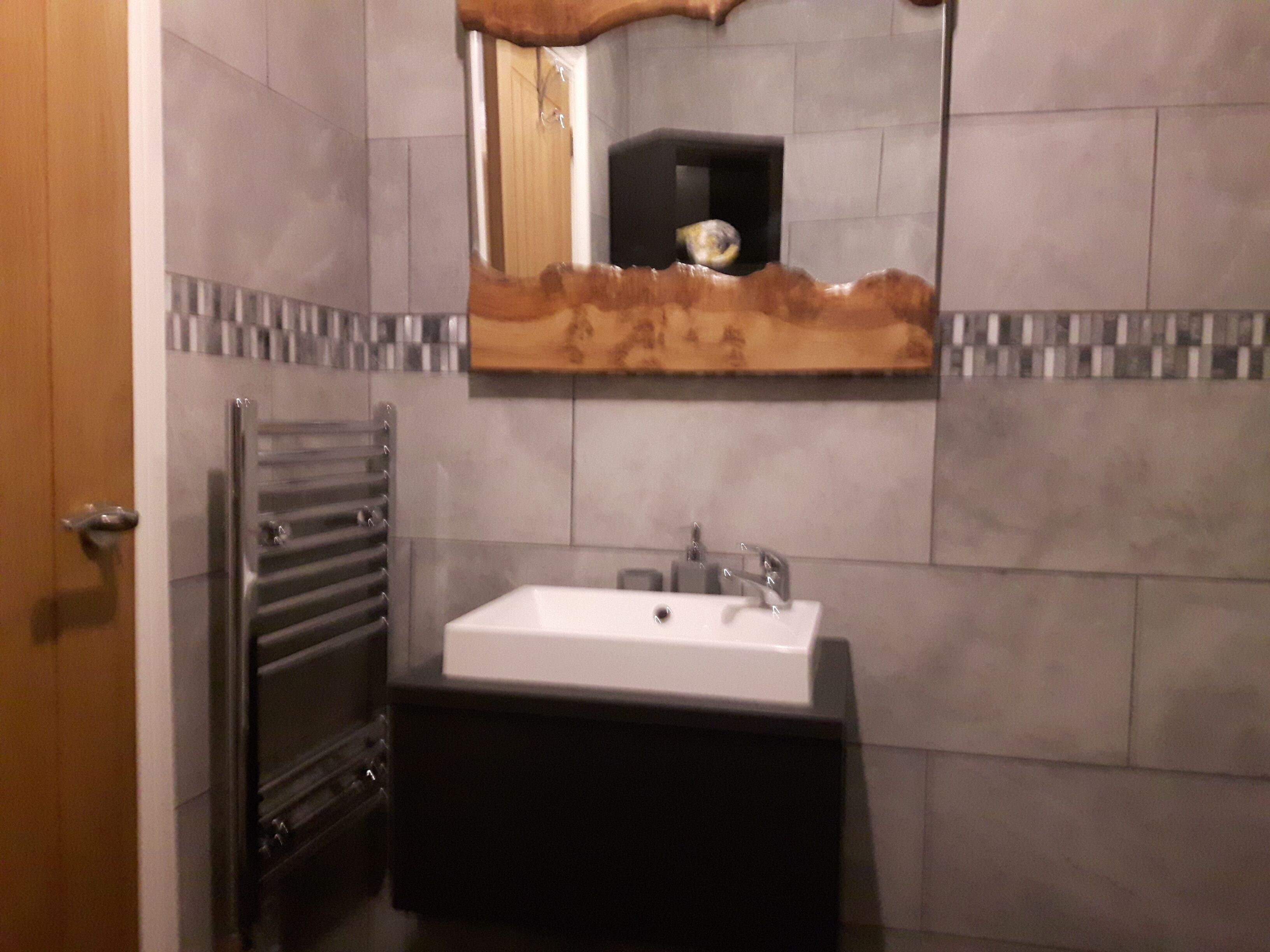 A bathroom with a white sink, a mirror with a wooden frame, and a towel rack.