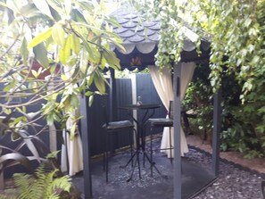 A covered outdoor seating area with two chairs and a table, surrounded by greenery and a decorative fence. - Ever Wanted to go off Grid,then This is for you (Sutton Coldfield)