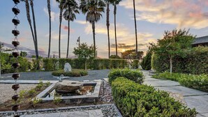 A landscaped garden with palm trees, a stone fountain, and a pathway. - 3BR Encinitas Family Retreat | Hot Tub & Fire Pit (Encinitas)