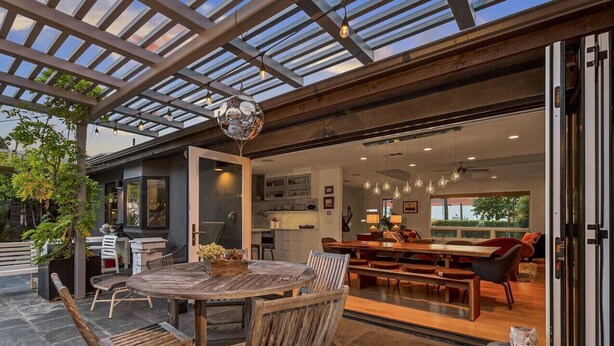 An open-plan living area with a wooden dining table and chairs, a kitchen in the background, and a glass ceiling. - 3BR Encinitas Family Retreat | Hot Tub & Fire Pit (Encinitas)