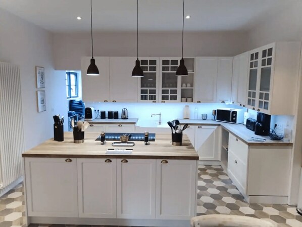 A modern kitchen with white cabinets, a central island, and pendant lighting.