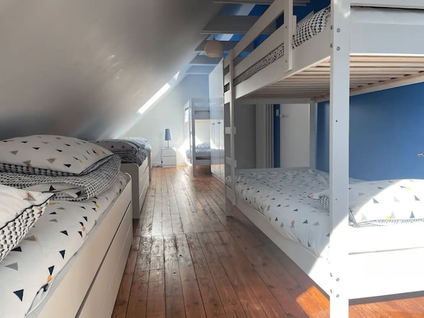 A room with two bunk beds, a wooden floor, and a window allowing natural light.