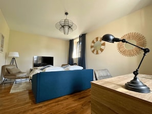 Habitación de hotel con cama, escritorio, silla, televisor y lámpara.
