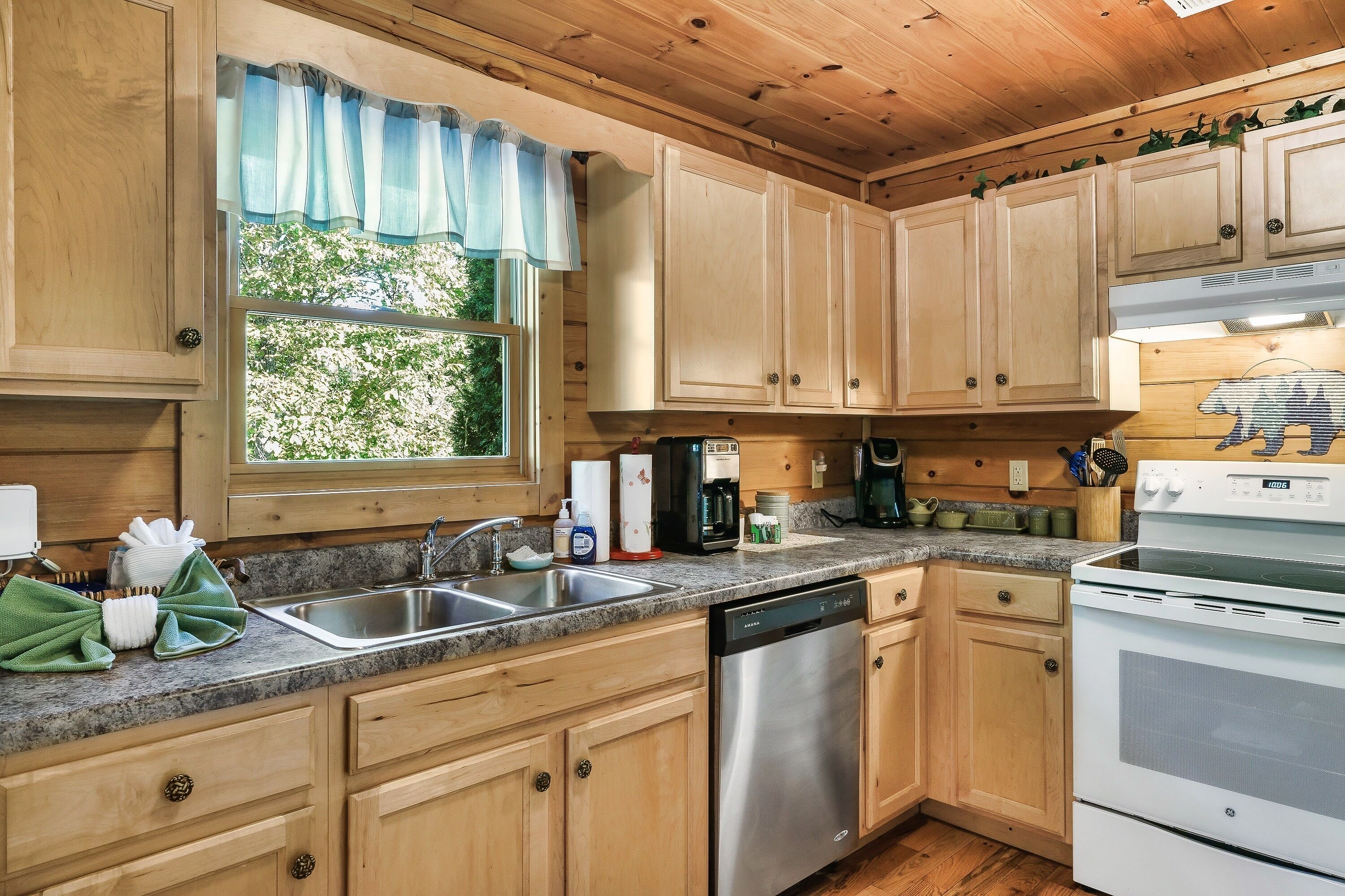 A kitchen with wooden cabinets, a stainless steel sink, a dishwasher, and a stove.