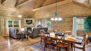 A spacious wooden cabin with a dining area, sofas, and a fireplace. - Fall Family Fun l Views, Hot Tub, Theater & Pool l 2 King Beds (Gatlinburg)