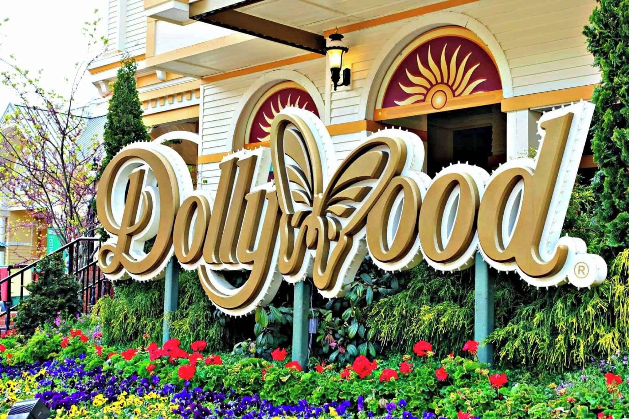 A large, ornate sign with the text "Polly Wood" in front of a building with a sun motif on the roof.