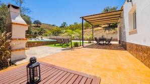 Un patio con una parrilla, mobiliario exterior y una piscina.