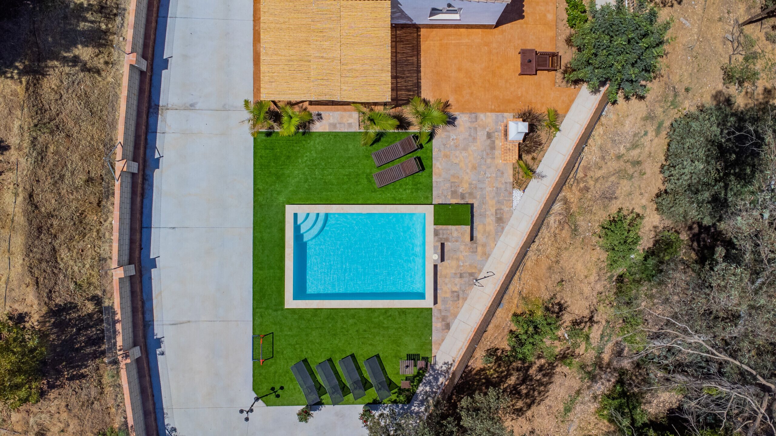 Vue aérienne d’une propriété dotée d’une piscine, d’un patio avec des chaises longues et d’une pelouse bien entretenue.