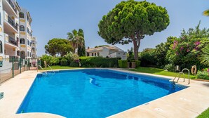 Ein Swimmingpool mit klarem, blauem Wasser, umgeben von einem gepflegten Garten mit verschiedenen Bäumen und Sträuchern.