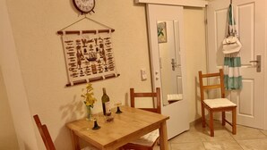 A dining area with a wooden table and chairs, a vase with flowers, a wine bottle, and a clock on the wall. - Apartment with sea view and pool - lemon garden (Kaluderac)