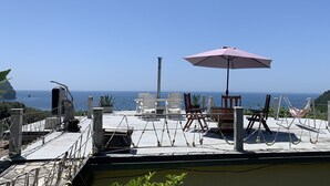 A terrace with outdoor seating, a hammock, and a view of the sea. - Apartment with sea view and pool - lemon garden (Kaluderac)