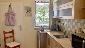 A compact kitchen with a window, a microwave, a sink, and a chair. - Apartment with sea view and pool - lemon garden (Kaluderac)