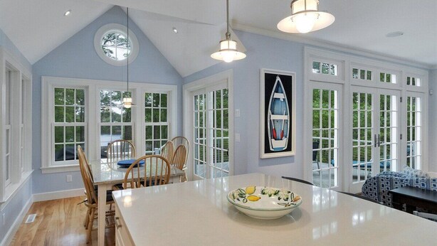 A spacious kitchen with a large island, white cabinetry, and a view through the windows.