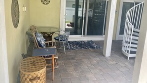 A covered patio area with a table and chairs, a ceiling fan, and a sliding glass door leading to an outdoor space. - One Bedroom Apartment, One block from the beach BTR #2197 (Indian Rocks Beach)