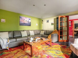 A living room with a grey sofa, a wooden coffee table, and a colorful rug.