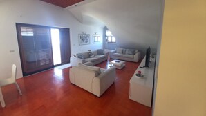 Een ruime woonkamer met een hoge plafond, een schuifdeur van glas en een rood plafondontwerp.