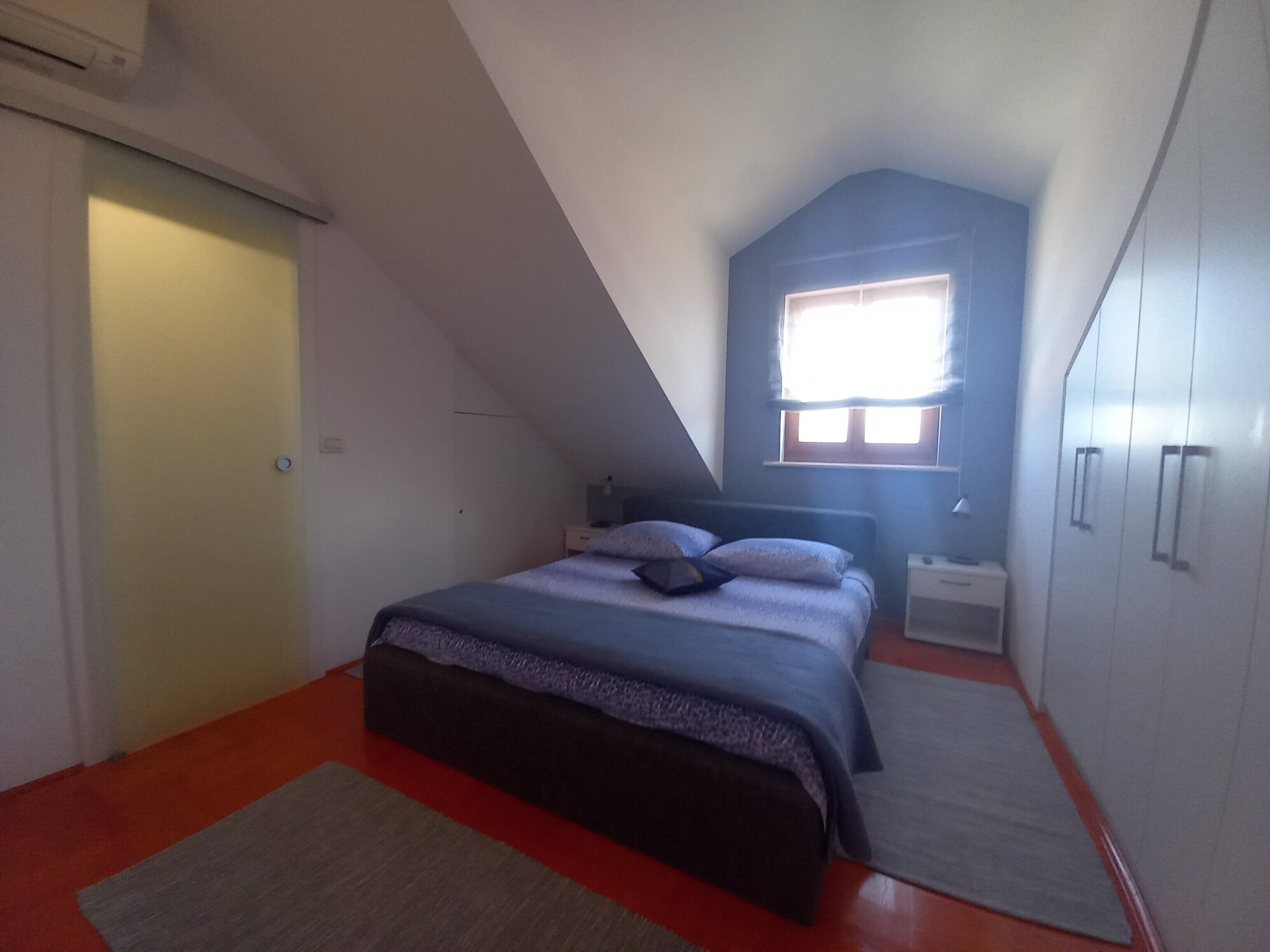 Una camera da letto con un letto, un comodino, un armadio, una finestra e una porta.