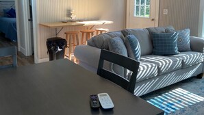 Kodikas olohuone, jossa on sohva, ruokapöytä ja pieni keittiöalue.