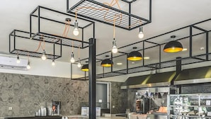 A modern bar area with high tables, stools, and pendant lighting. - Althea Village Hotel (Chania)