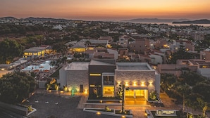 A modern hotel with a pool, surrounded by residential buildings, during sunset. - Althea Village Hotel (Chania)