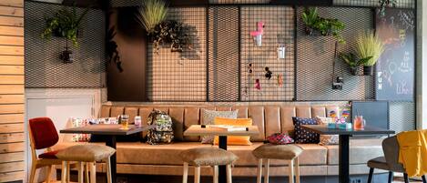 A modern cafe with a wooden bench, stools, and a small table with drinks and snacks.
