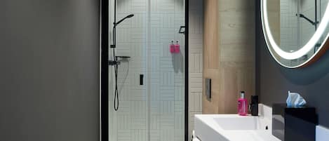 A modern bathroom with a glass-enclosed shower, a white toilet, and a vanity with a mirror.