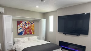 Una camera da letto con un letto, una TV, un camino e un quadro colorato.
