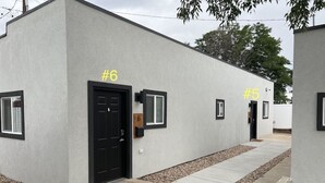 Un edificio moderno con porte numerate, numero 6 e numero 5, e un vialetto in cemento che conduce all'ingresso.