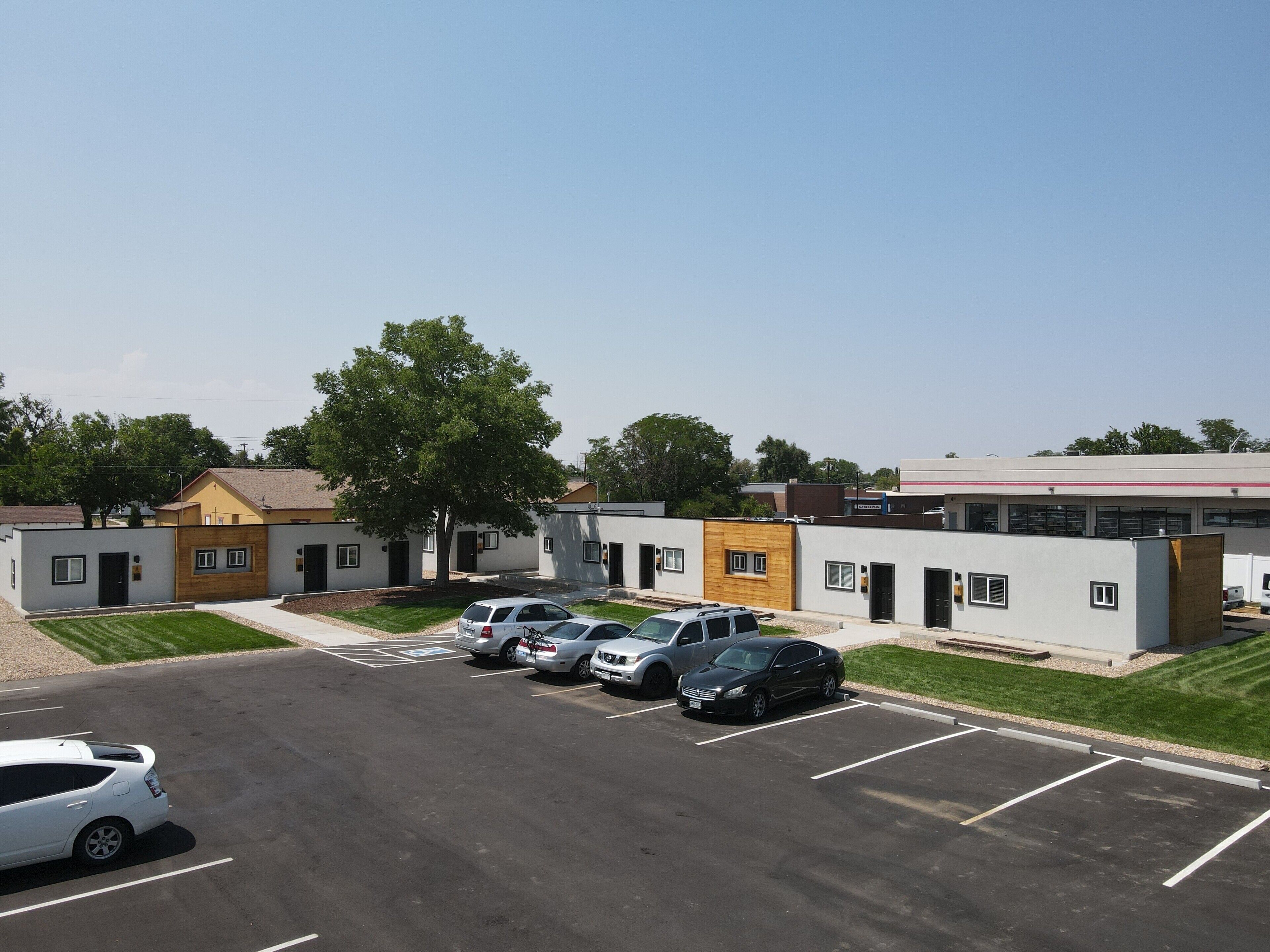 A parking lot with several cars and a building with multiple doors and windows.