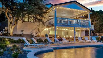 A two-story house with a balcony, a swimming pool, and outdoor seating.