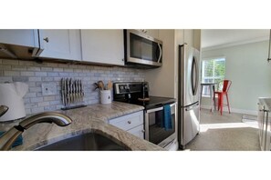 Enjoy cooking in this well-equipped kitchen with a microwave, stainless steel sink, and granite countertop.