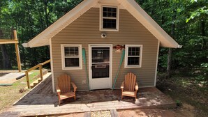 Una cabaña pequeña con terraza, dos sillas Adirondack y un letrero que dice 'B&B'.