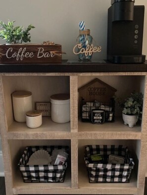 A coffee-themed shelf with a coffee bar sign, a coffee maker, and storage bins.