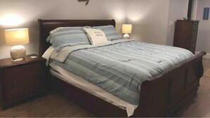 A bedroom with a bed, two bedside lamps, a ceiling fan, and a wall decoration.
