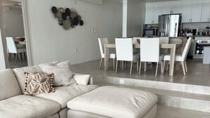 A modern living room with a sectional sofa, a coffee table, and a dining area with a table and chairs. - Stunning Beach Front Villa With Infinity Pool  (Pelican Key, Simpson Bay)