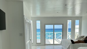A spacious bedroom with a large sliding glass door leading to a balcony with a view of the ocean. - Stunning Beach Front Villa With Infinity Pool  (Pelican Key, Simpson Bay)