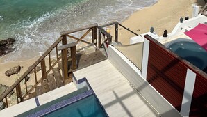A beach view with a wooden deck, a swimming pool, and a clear blue ocean. - Stunning Beach Front Villa With Infinity Pool  (Pelican Key, Simpson Bay)