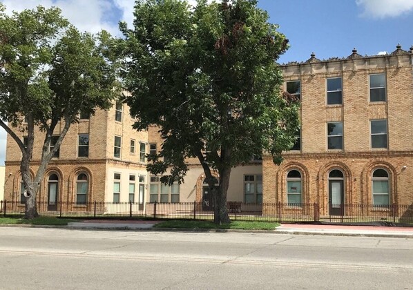 A multi-story brick building with arched windows and a central entrance. - Stay in a Restored 1929 Hotel in Downtown Bay City, TX (Bay City)
