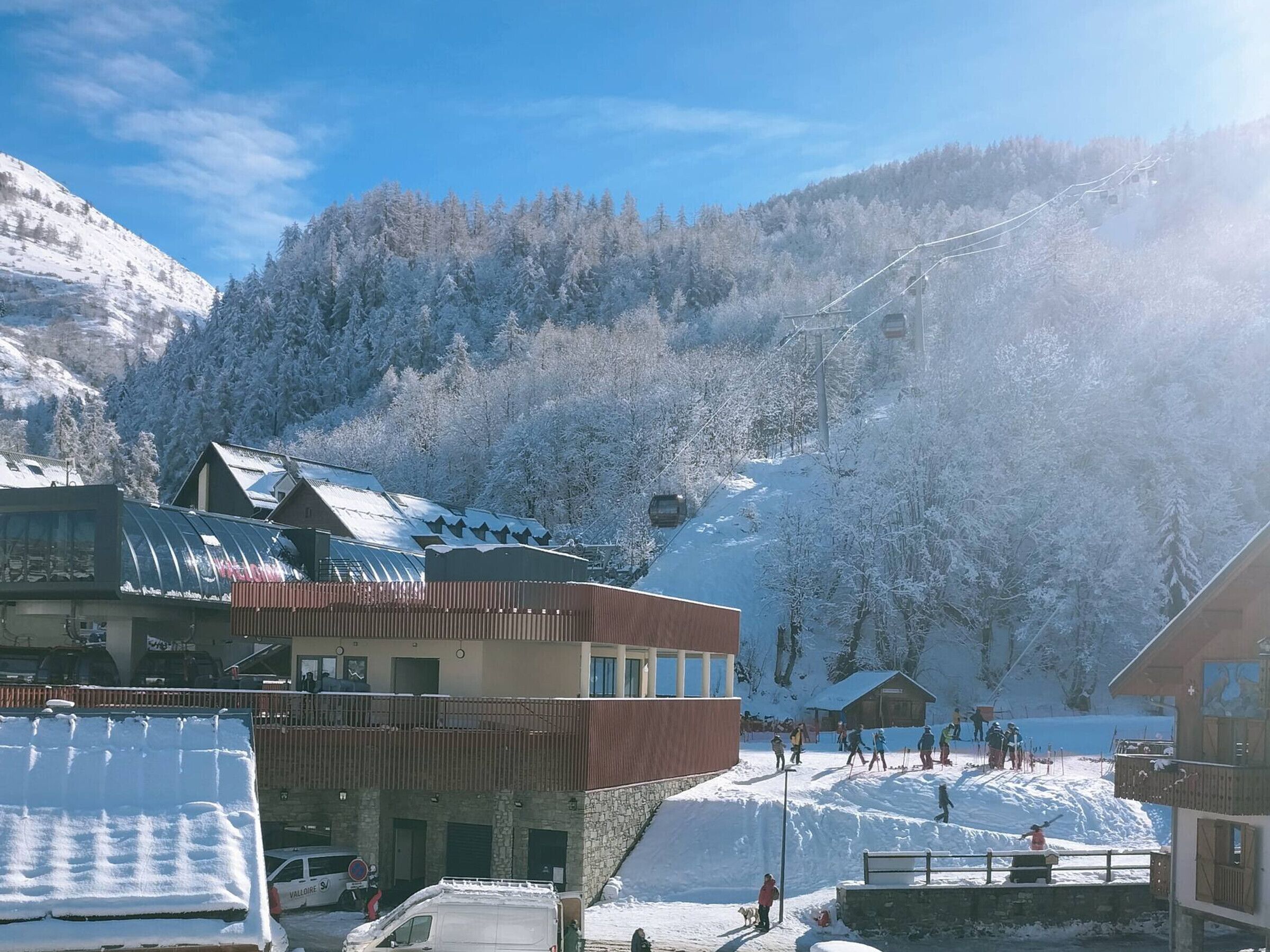 Un paese montano innevato con edifici, una seggiovia e cielo sereno.