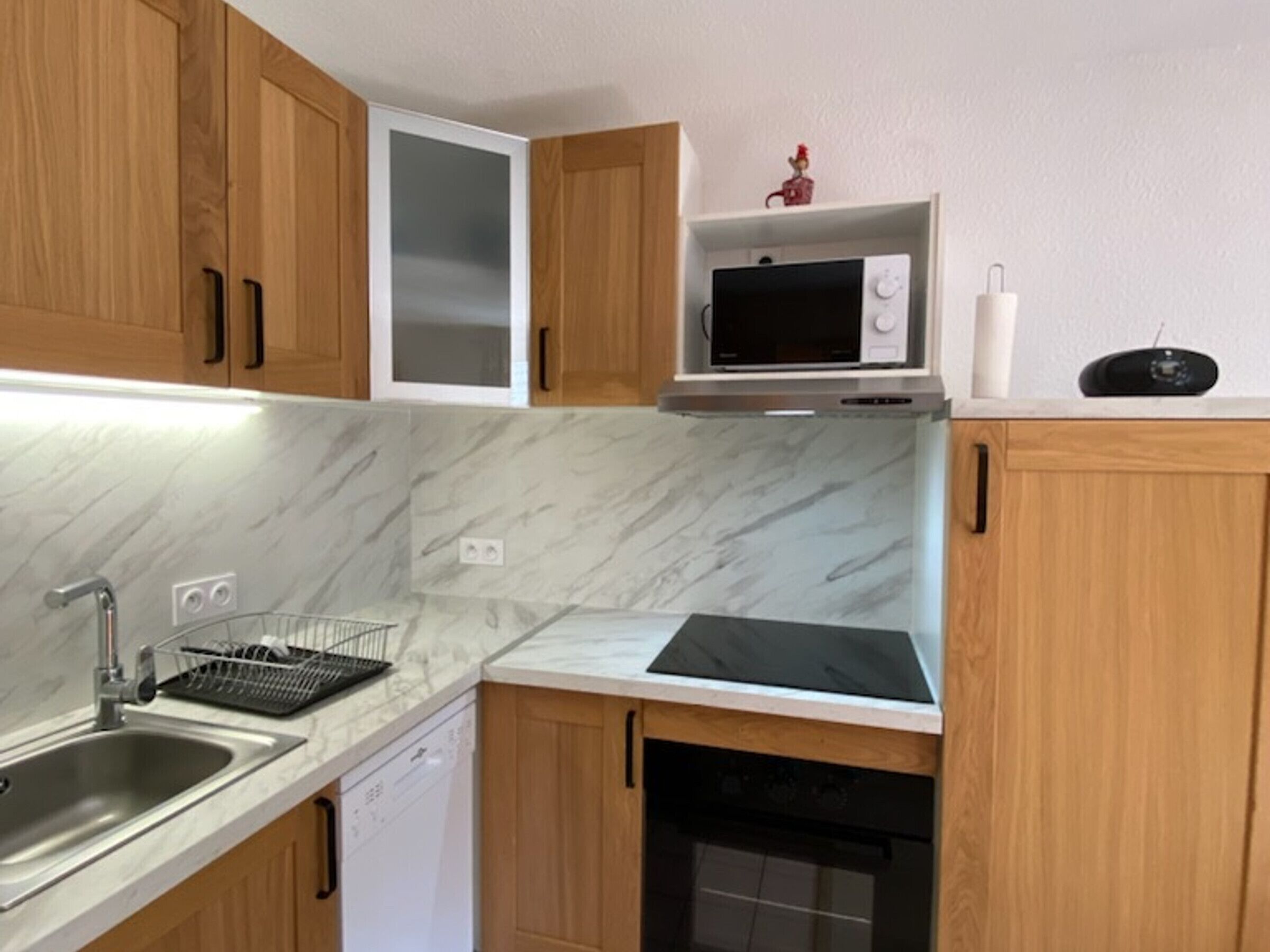 Una cocina con armarios de madera, microondas, tostadora y lavavajillas.