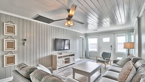 Una sala de estar con techo de madera, un ventilador de techo, televisor, sofá, mesa de centro y lámpara.