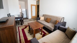 Ein Wohnzimmer mit einer Couch, einem Couchtisch, einem Fernseher und einem Essbereich mit Stühlen und einem Tisch.