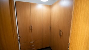 Ein begehbarer Kleiderschrank mit Holztüren, einer Deckenleuchte und einem Teppichboden in Schwarz.