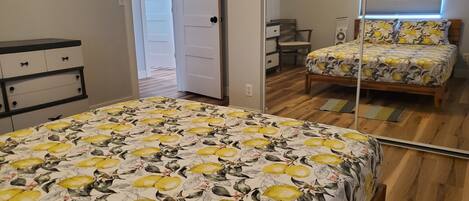 A bedroom with a bed, a dresser, a mirror, and a door leading to another room.
