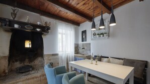 A cozy dining area with a white table and blue chairs, a fireplace, and a wooden ceiling. - Valesi holiday home (Rakalj)