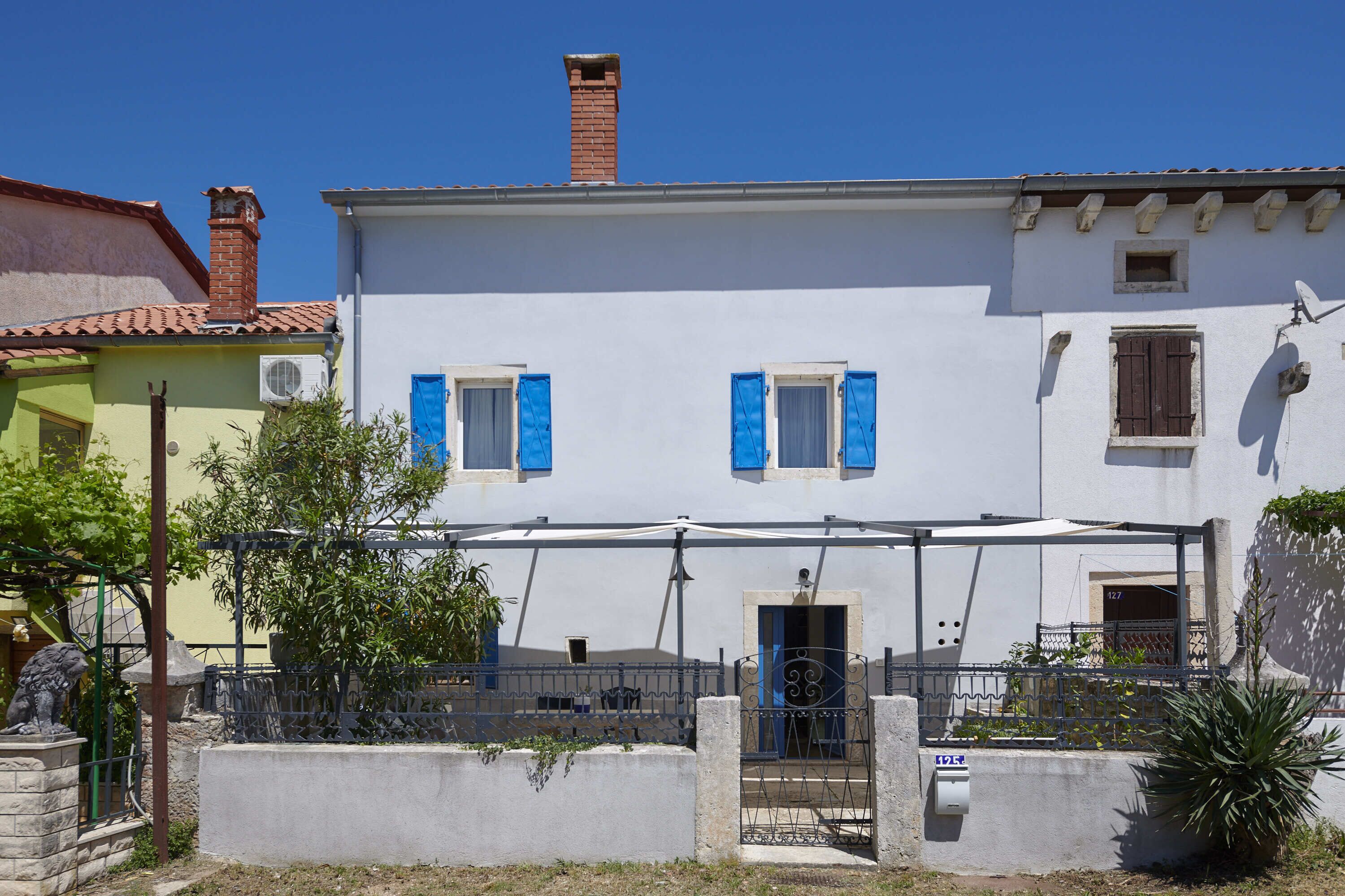 A white building with blue shutters, a brick chimney, and a satellite dish.