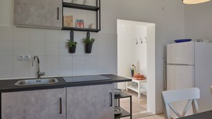 A modern kitchen with a black countertop, stainless steel sink, and a white refrigerator. - Valesi holiday home (Rakalj)
