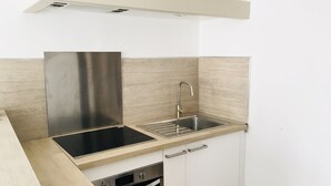Una cucina compatta con cappa in acciaio inossidabile, lavello e forno integrato.
